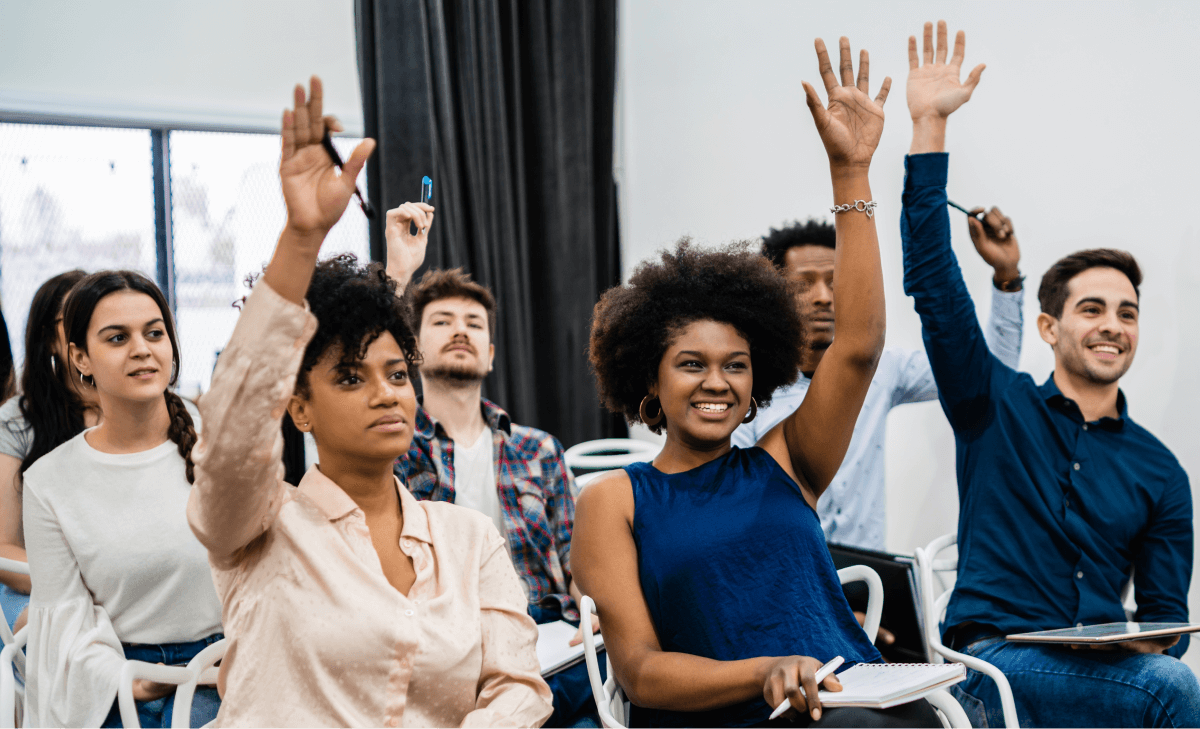 Group of diverse people raising hands in a classroom