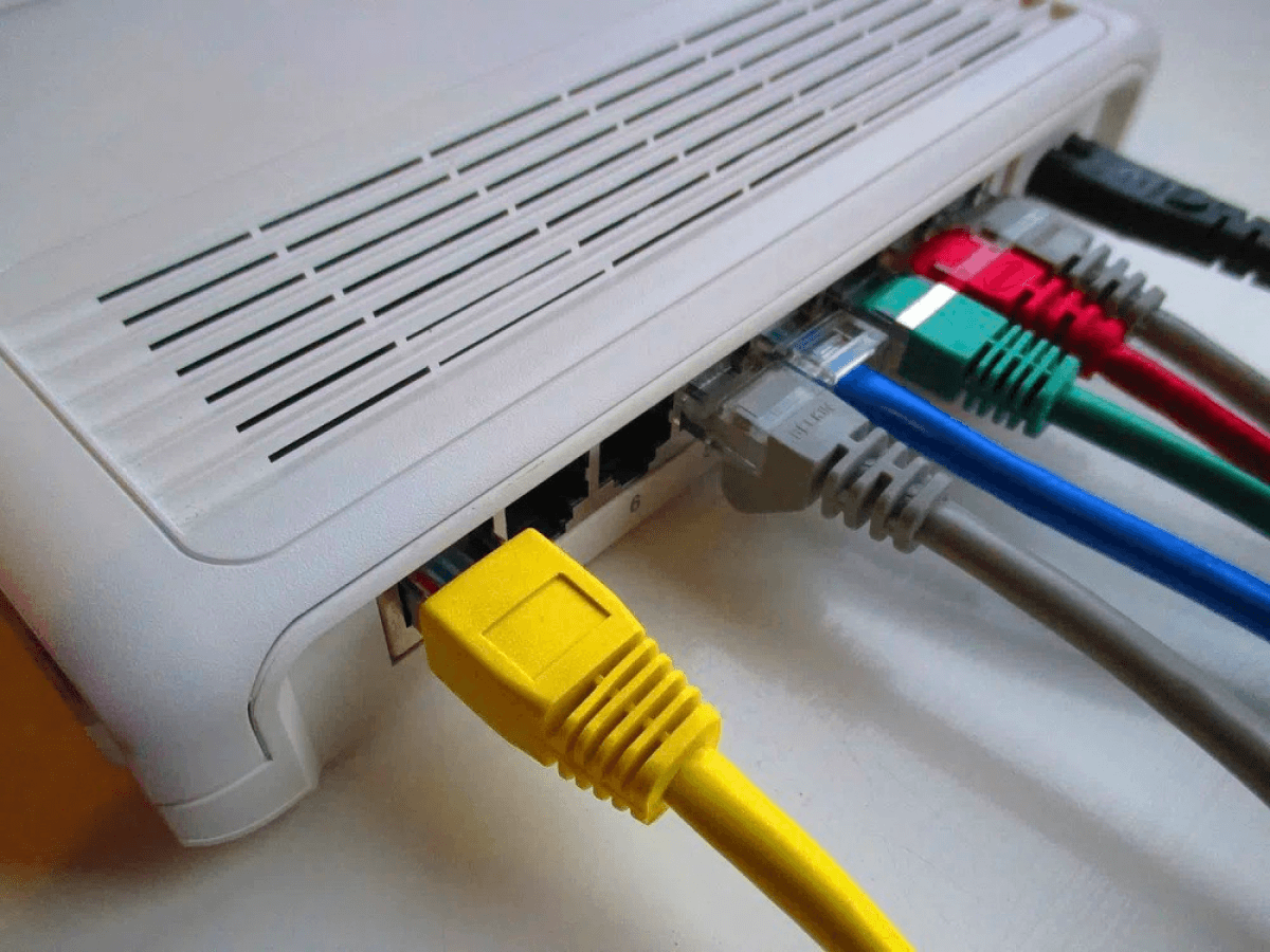 A white modem with different colored ethernet cables in it